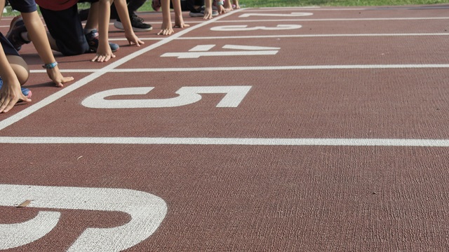 Runners poised to begin a race on a red athletics track