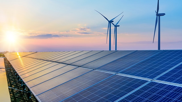 image showing a solar farm with a windmill in the background